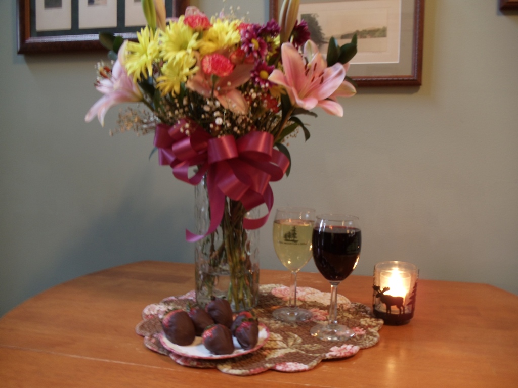 flowers in a vase, wines, and chocolate-covered strawberries